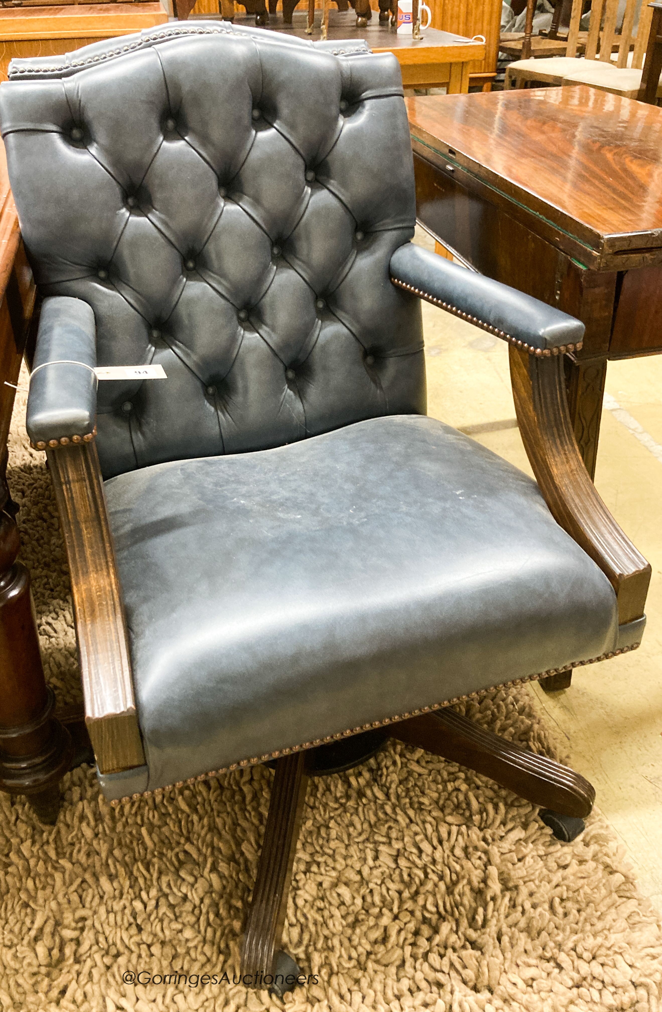 A pair of reproduction beech buttoned blue leather swivel desk chairs, width 60cm, depth 55cm, height 90cm